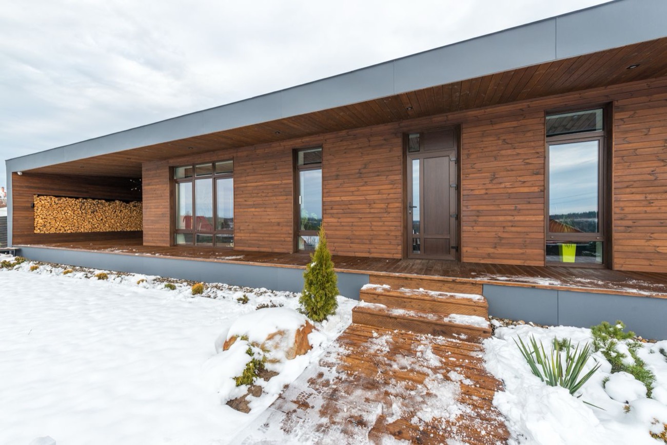 Maison en bois avec réserve de bûches sous la neige en hiver